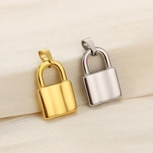 Close-up of polished gold and silver lock pendants on soft white silk fabric background