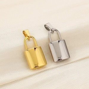 Polished gold and silver padlock charms on beige silk background showing metallic texture
