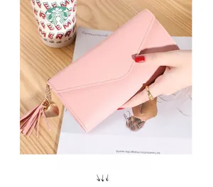 Detail of pink long envelope wallet with tassel heart charm and litchi texture