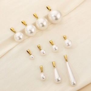 Detail showing white round and teardrop pearl pendants with golden clasps on textured fabric