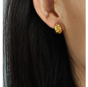 Detail of gold spiral horn earrings showing textured grooves and metallic finish