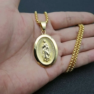 Dettaglio del ciondolo Madonna placcato oro con catena box sul palmo della mano
