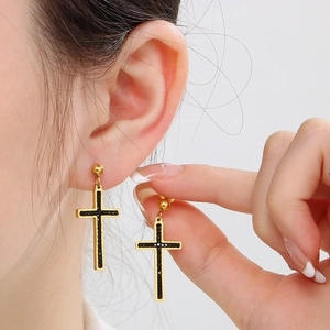 Macro shot of gold cross earrings with black crystals and gothic tassel detail