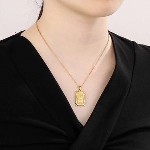 Detailed macro view of 18k gold plated rectangular pendant with letter B and sunburst texture
