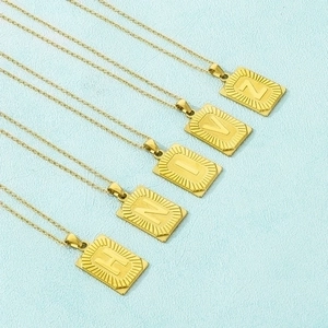 Detail of five 18k gold plated rectangular letter pendants with radial texture