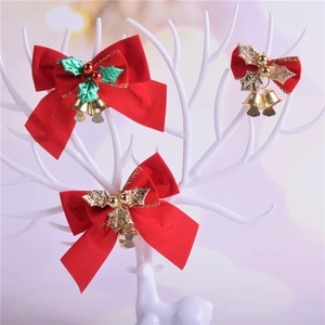 Three red Christmas bows with gold bells and holly leaves on a white stag antler display