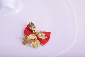 Detail of red Christmas bow with golden holly leaves and hanging metal bells ornament