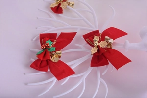 Close-up of red festive Christmas bow with gold bells and holly leaves on a white branch