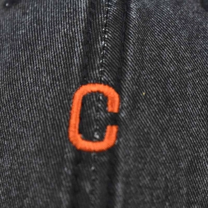 Macro shot of orange embroidered letter C on black washed vintage cotton baseball cap