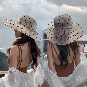 Detail view of beige sun hat with black polka dots and layered flower decoration