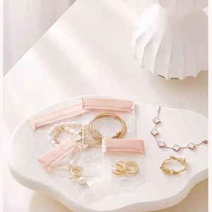 Pink EVA jewelry storage bags for necklaces and earrings shown on an elegant tray