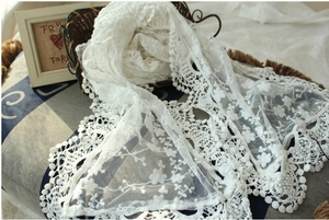 Detail showing white lace scarf with intricate floral embroidery and scalloped edges