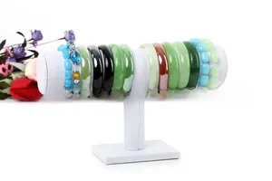 Close-up of assorted jade bracelets and bead anklets on a white T-bar jewelry display stand