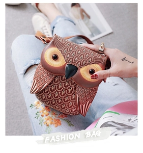 Detail of owl-shaped crossbody bag featuring feather embossed texture and leather strap