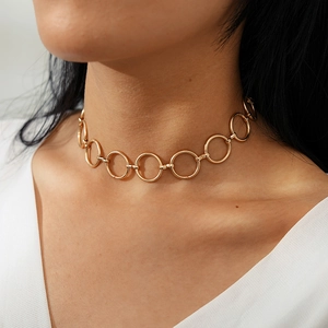 Gros plan d'un collier ras du cou géométrique doré montrant des anneaux métalliques lisses