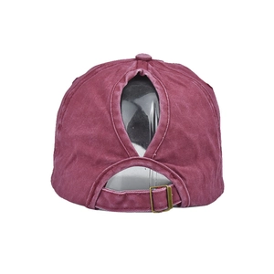 Close-up of ponytail opening and adjustable metal buckle on burgundy washed baseball cap