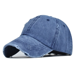 Close-up of vintage washed denim baseball cap featuring distressed torn details and blue texture