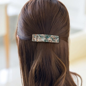 Gros plan d'une pince à cheveux carrée en acétate à motif marbre sur modèle