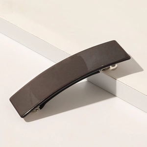 Détail d'une pince à cheveux rectangulaire marron foncé nacrée sur un support blanc