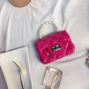 Top view of rose red mini jelly bag with quilted texture and pearl handle on white cloth
