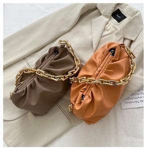 Detail of ruched cloud bags in dark brown and orange with chunky gold chain straps