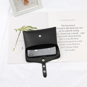 Detail showing a black leather phone pouch with snap closure holding a mobile phone