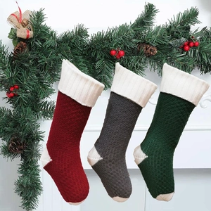 Detailed texture of cable knit Christmas stockings in burgundy, grey, and forest green