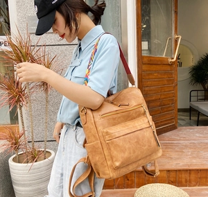 Détail d'un sac à dos vintage en cuir PU marron avec bandoulière tissée géométrique colorée