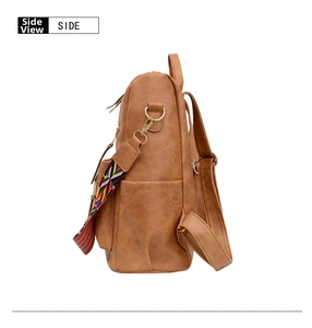 Détail du sac à dos en cuir marron avec bandoulière tissée ethnique et boucles dorées