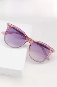 Détail de lunettes de soleil carrées avec monture rose translucide et charnière en métal doré