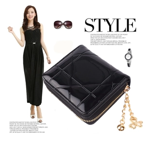 Detail der schwarzen Lackleder-Brieftasche mit Steppmuster und goldenem Kleeblatt