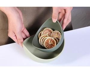 Close-up of matte ceramic lotus bowls in Morandi green held by hand with dried fruit