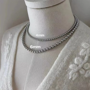 Elegant 4mm and 6mm silver grey pearl necklace display on white knit background
