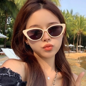 Fashionable beige cat-eye sunglasses with dark grey lenses for a beach vacation look