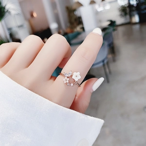Detail of rose gold flower ring with small white petals, pearls and sparkling crystals