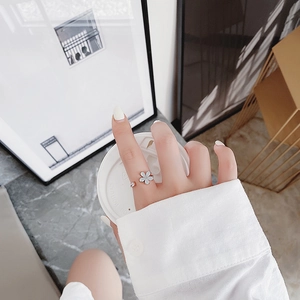 Elegant rose gold flower ring with zircon detail worn by a model in a cafe setting
