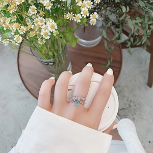 Detailed shot of flower ring with blue teardrop gemstone and silver petal texture