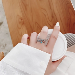 Detail of silver floral ring with blue teardrop crystal and stones worn on hand