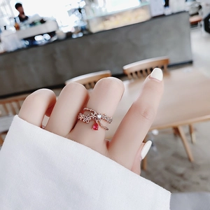 Detail of rose gold flower ring featuring micro-pave crystals and a red pear-cut pendant