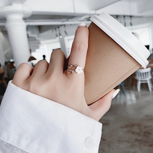 Detail of rose gold flower ring with crystals while holding a coffee cup