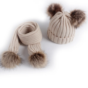 Children's beige knit hat and scarf set with brown faux fur pompoms on white background