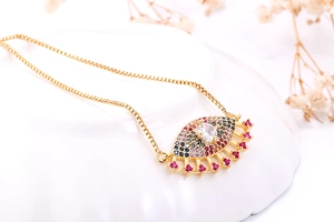 Detail van gouden Evil Eye ketting met gekleurde zirkoon op een wit keramisch plateau