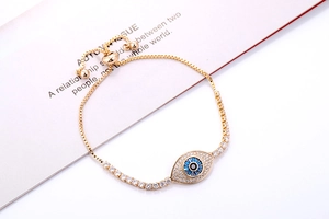 Detailopname van de gouden verstelbare evil eye armband met blauwe steen en zirkoon