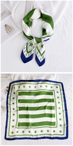 Detail of green and blue silk scarf with stripe and star patterns and blue edges