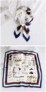 Detail of equestrian silk scarf featuring stirrups and harness patterns in navy and gold