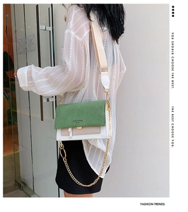 Detail of green and white color-block crossbody bag with gold chain and wide strap