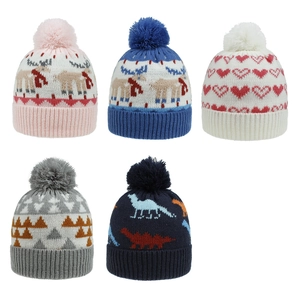 Detail showing five knitted winter beanies with soft pom-poms and colorful dinosaur patterns