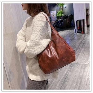 Side view of brown hobo shoulder bag with soft leather texture and logo detail