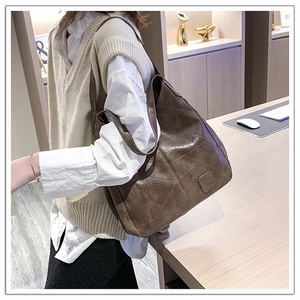 Detail view of deep brown faux leather tote bag with stylish decorative stitching and logo