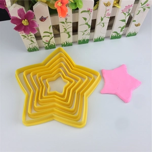 Macro detail of star-shaped yellow plastic cookie cutters with pink dough cutout